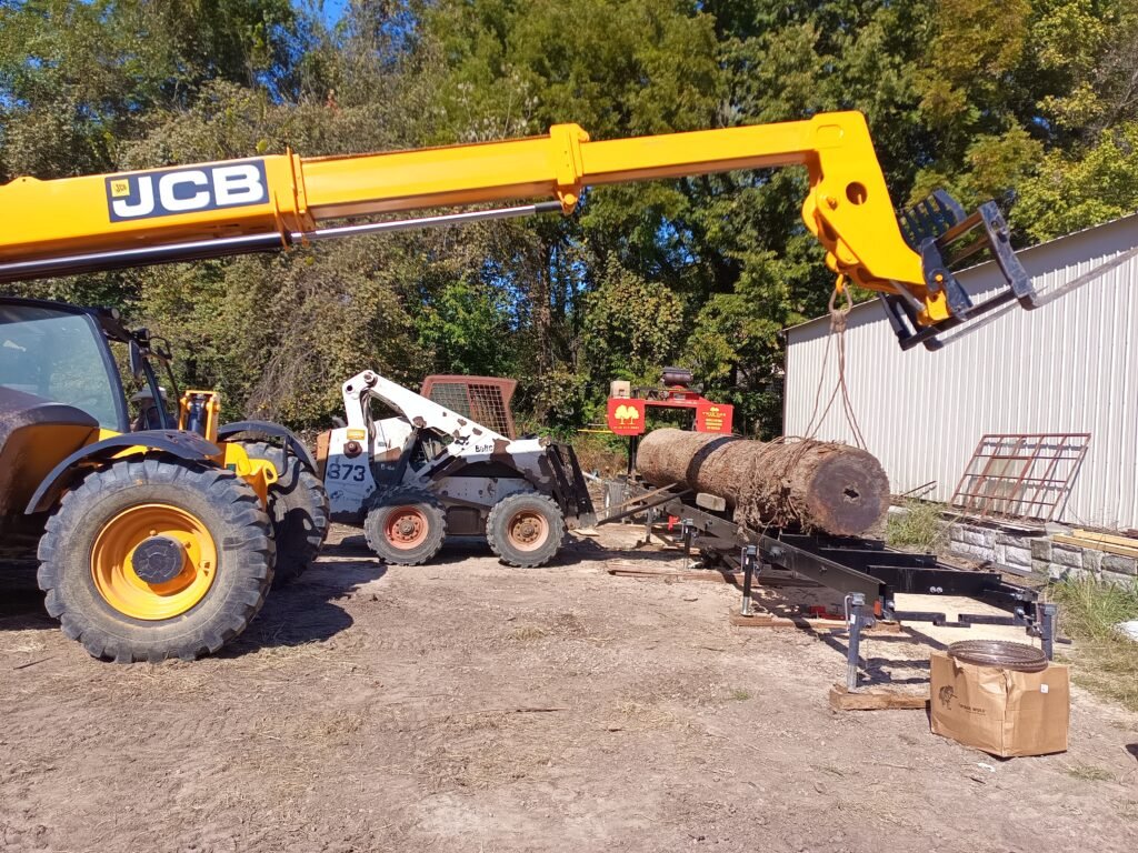 Telehandler loading a big log onto the sawmill